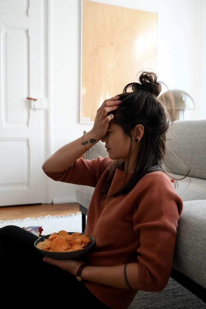 Stefanie Grace sitzt mit einem Teller Chips und blickt frustriert.